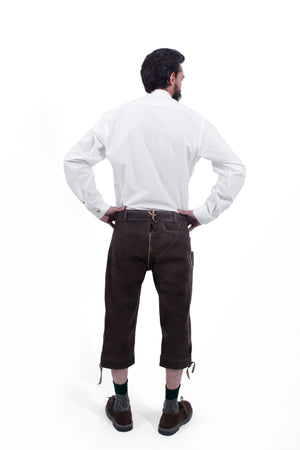 Rear view of a man wearing traditional dark brown leather Bundhosen and a white shirt. The image showcases the back details of the Bundhosen, including the tie straps and embroidery on the back pocket. The man is also wearing traditional Bavarian socks and shoes.