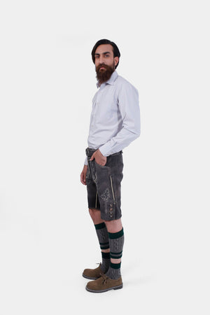 back view of a bearded man standing confidently in Black Forest Lederhosen, complete with knee-high socks and traditional shoes.