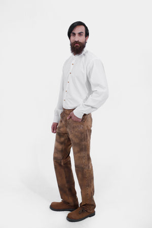 Side view of a man wearing traditional lederhosen long pants paired with a plain white shirt and brown shoes