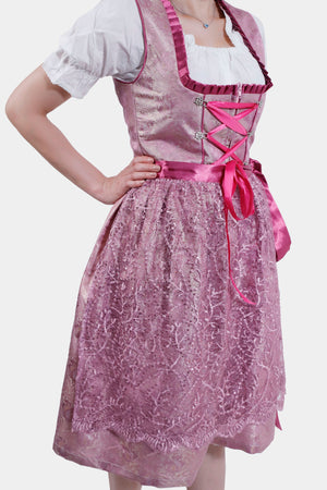 Detail shot of the lace skirt and pink satin ribbon on the pink dirndl, paired with the white blouse's puffed sleeves.