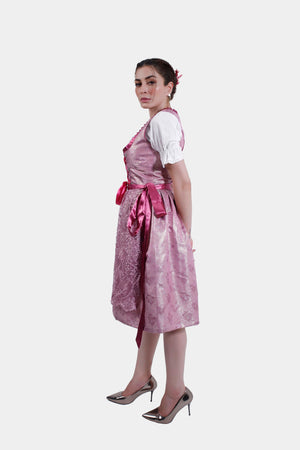 Angled front view of the pink dirndl, showing the intricate lace overlay on the skirt and the satin ribbon lacing on the bodice.