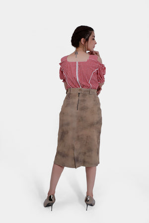 Back view of the woman wearing the red and white checkered blouse and beige leather skirt. The back of the blouse has a zipper, and the skirt features a slit at the back.