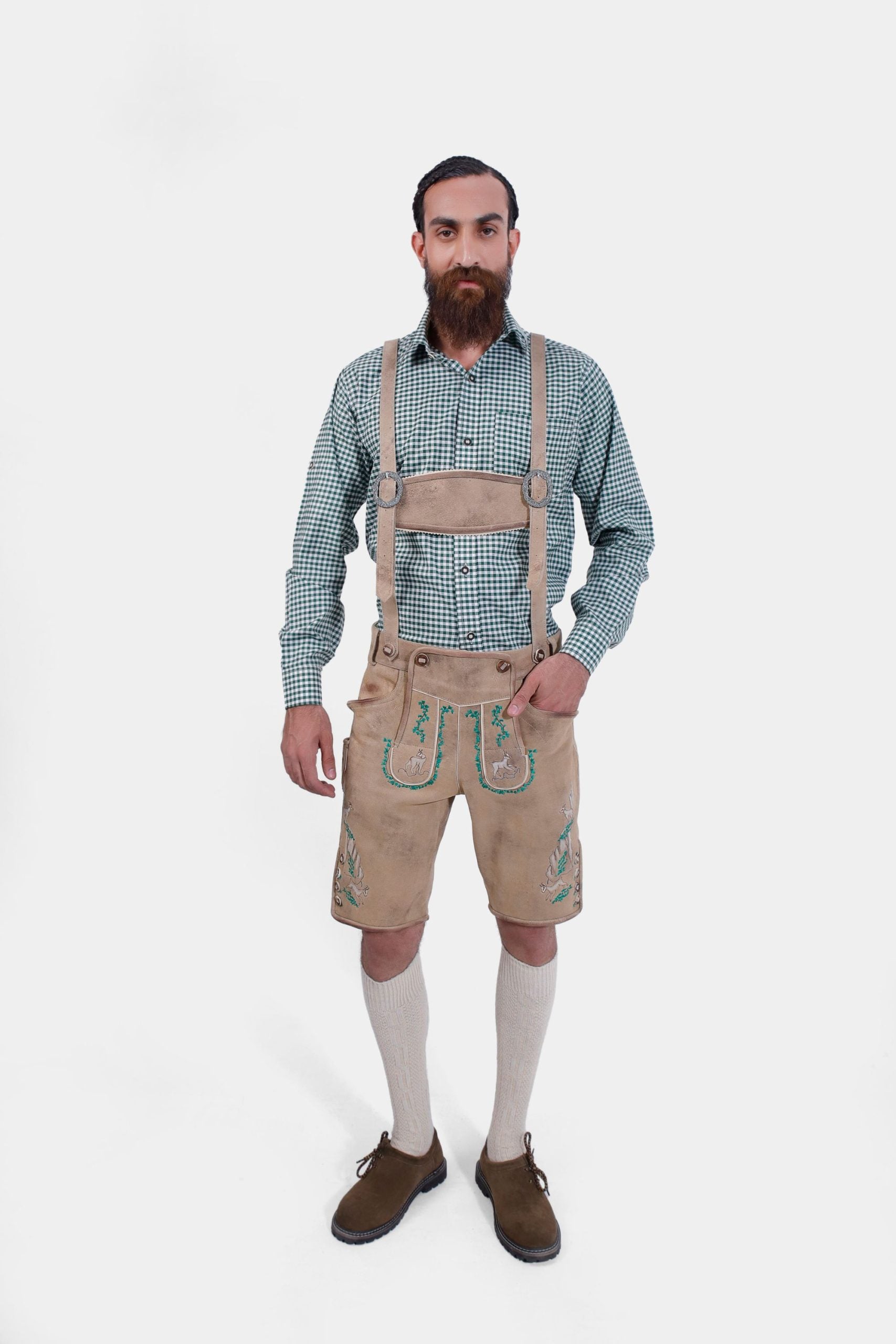 Man wearing traditional Lederhosen with green checkered shirt, light brown leather suspenders featuring green embroidery with deer motifs, named 'Edersee Wood Suspender.