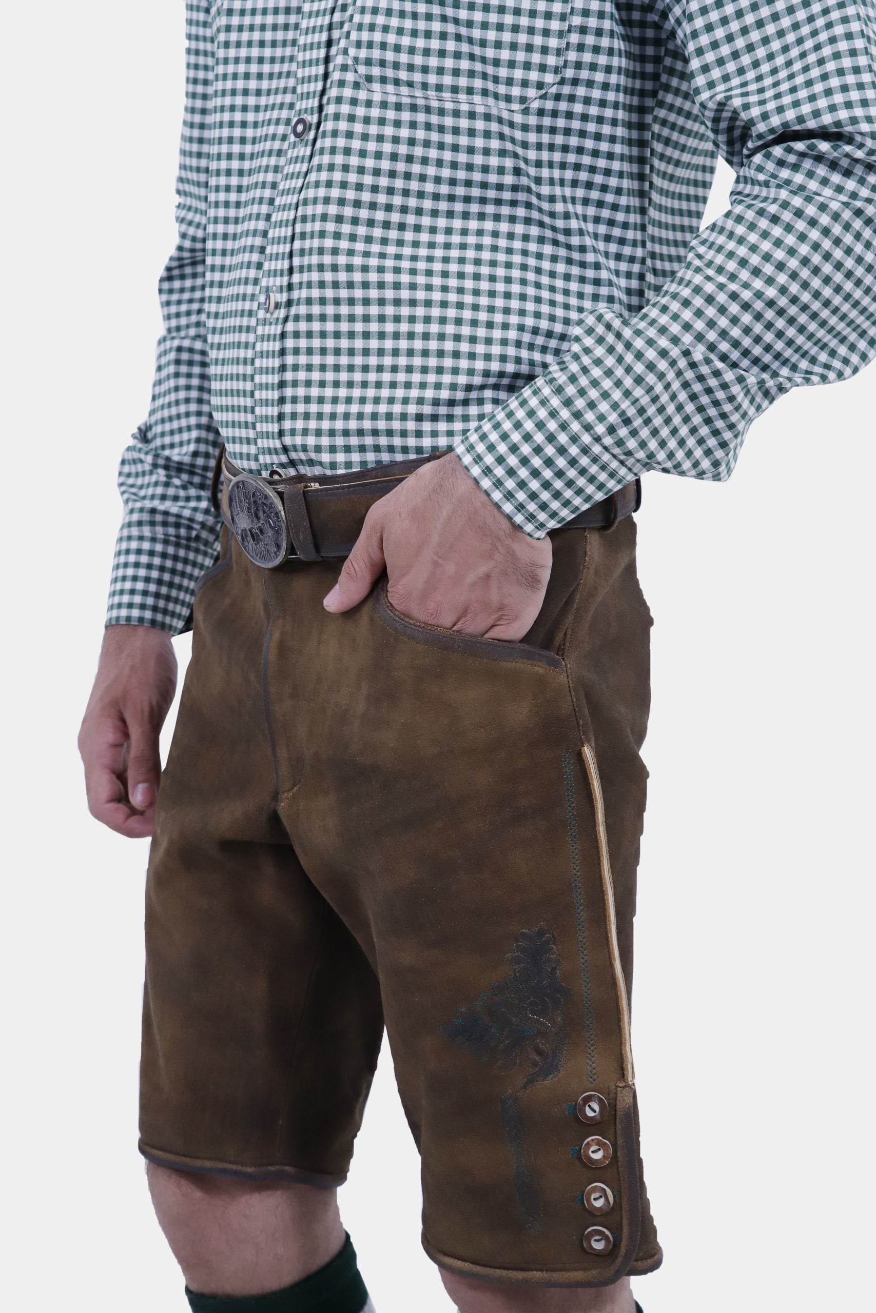Side view of a man wearing traditional brown leather cargo Lederhosen paired with a green checkered shirt. The image highlights the side pockets and the belt buckle.