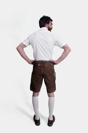 The man poses from the back, displaying the fit and stitching details of the brown lederhosen.