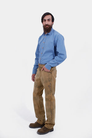 Complete side view of a man wearing Kochelsee Lederhosen Long pants paired with light blue checkered shirt