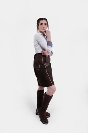 Full-body side shot of a woman wearing the Lillian Lederhosen Skirt, styled with a white blouse and boots.