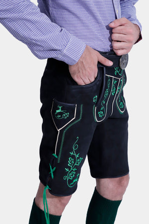 A side view of a man wearing the Mueller Lederhosen, highlighting the detailed embroidery and side ribbon ties, with his hand in his pocket.