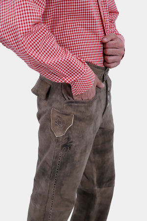 side view of a man wearing lederhosen long paired with red checkered shirt