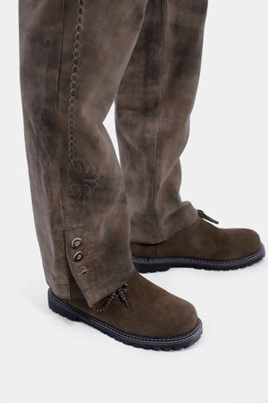 Closed side view from bottom of a man wearing lederhosen long paired with brown matching shoes