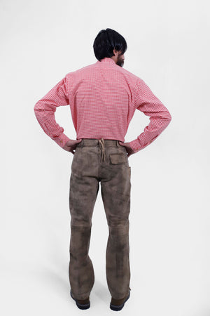 back view of a man wearing long lederhosen pants paired with red checkered shirt