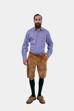 Full front view of a man wearing a blue and white checkered dress shirt and brown cargo lederhosen with pockets. He is standing with his left hand in his pocket, facing the camera.