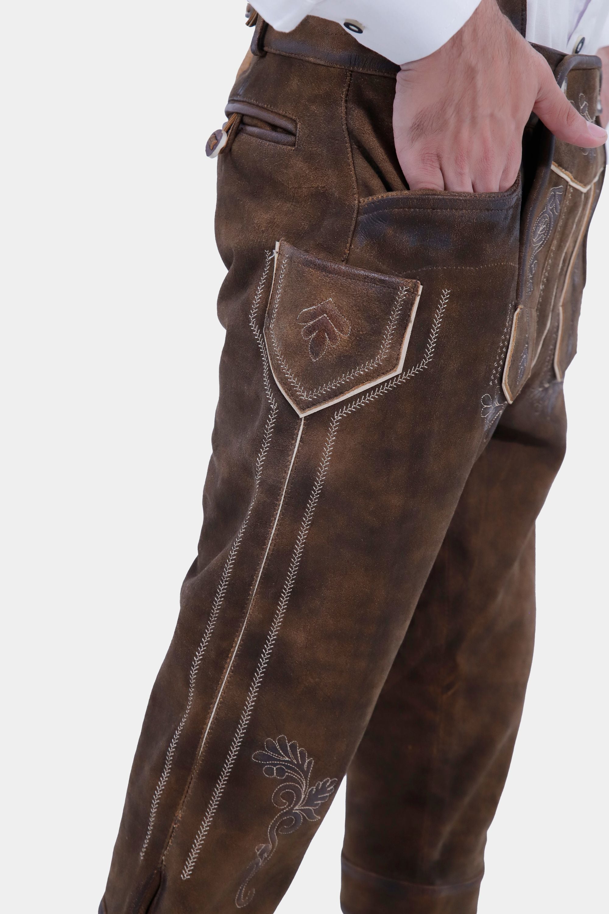 Close-up of brown lederhosen side, showing detailed embroidery and a front pocket with the man's hand partially inside.