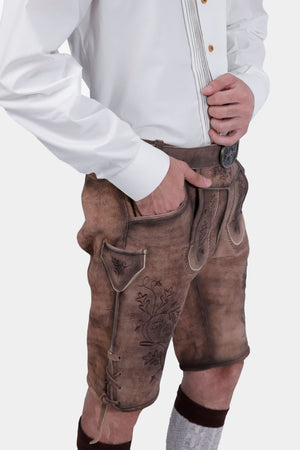 Closed side view of a man wearing Timber Trail Lederhosen in Caramel Earth with natural embroidery, goat suede leather, and multiple pockets.