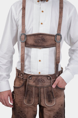 Closed front view of a man wearing Timber Trail Lederhosen in Caramel Earth with suspenders in natural embroidery, goat suede leather.