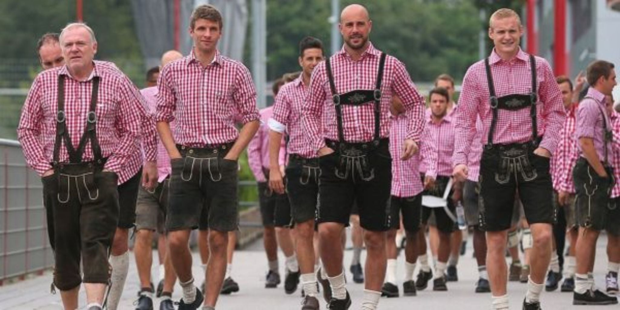 Men wearing Bavarian Lederhosen and red checkered shirts at a festive event.