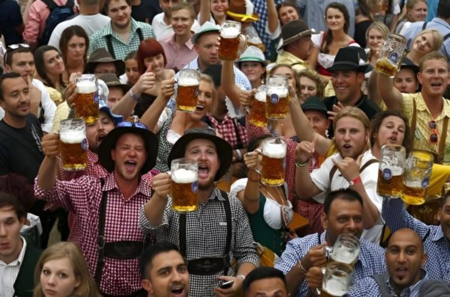 Group of people in traditional German clothing raising beer mugs and cheering at Oktoberfest