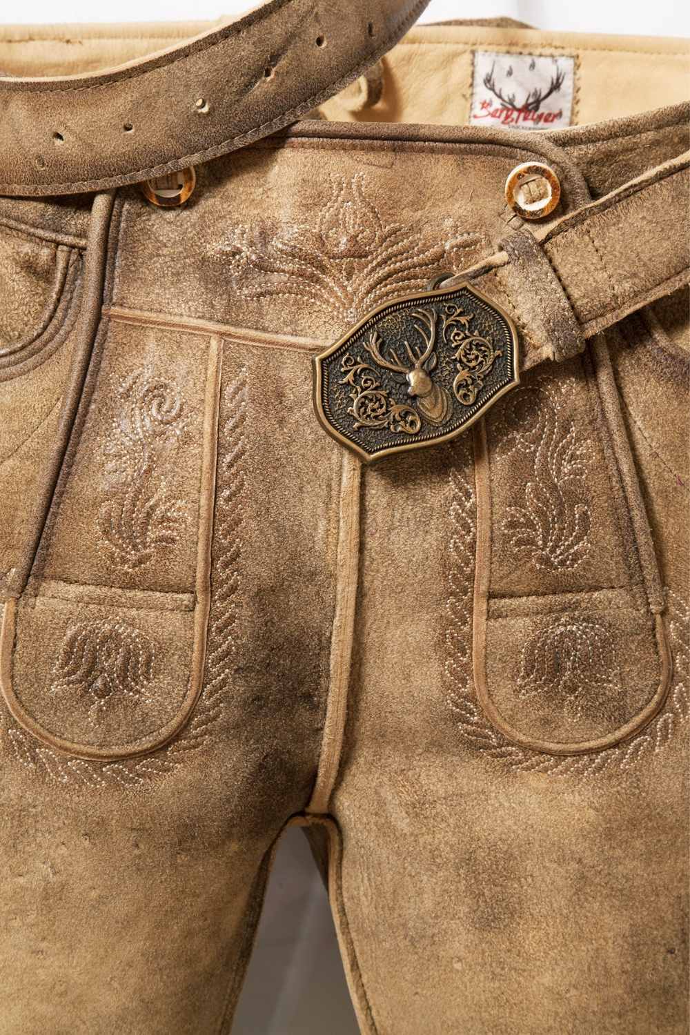 A close-up of German lederhosen shorts showcasing fine craftsmanship, including a decorative belt buckle and detailed stitchwork. These lederhosen short shorts are designed for durability and style during Oktoberfest events