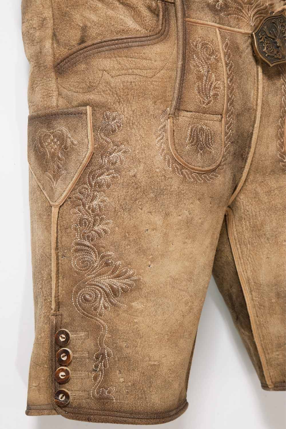 Side view of mens Oktoberfest shorts highlighting the fine leather texture and ornate embroidery along the leg seams. These German lederhosen shorts provide comfort and tradition in one stylish package