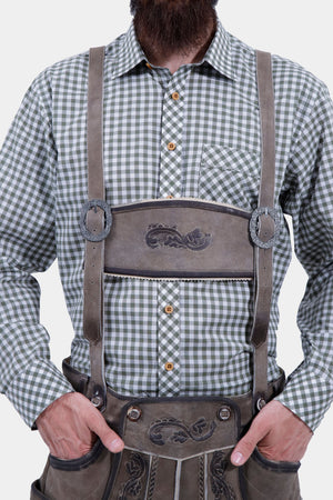 Close-up of the man's upper body, showing the green checkered shirt and brown Lederhosen with suspenders. The suspenders feature silver buckles and detailed embroidery on the front panel.