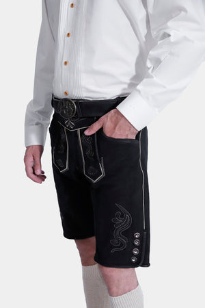 Closed side view of a man wearing Black Edelweiss Lederhosen in Obsidian Twilight with natural embroidery, white shirt