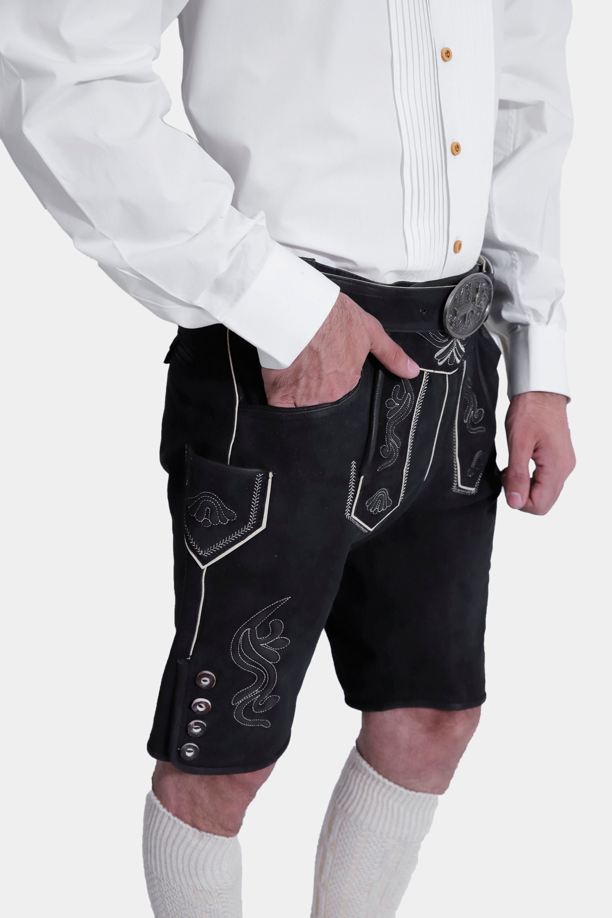 Closed side view of a man wearing Black Edelweiss Lederhosen in Obsidian Twilight with natural embroidery, white shirt