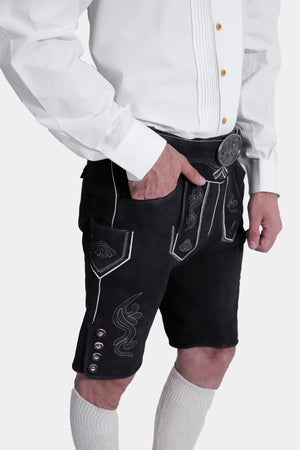 Closed side view of a man wearing Black Edelweiss Lederhosen in Obsidian Twilight with natural embroidery, white shirt