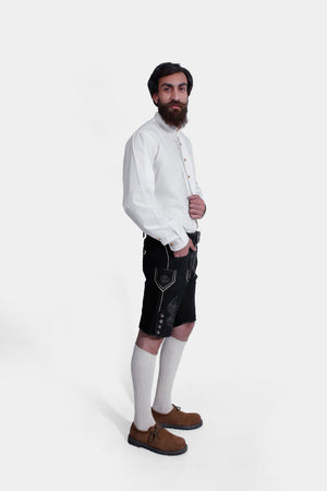 Side view of a man wearing Black Edelweiss Lederhosen in Obsidian Twilight with natural embroidery, white shirt, and traditional knee-high socks.