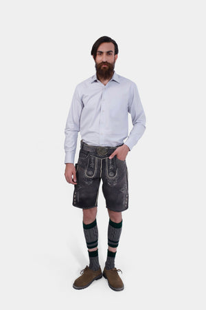 A bearded man standing confidently in Black Forest Lederhosen, complete with knee-high socks and traditional shoes.