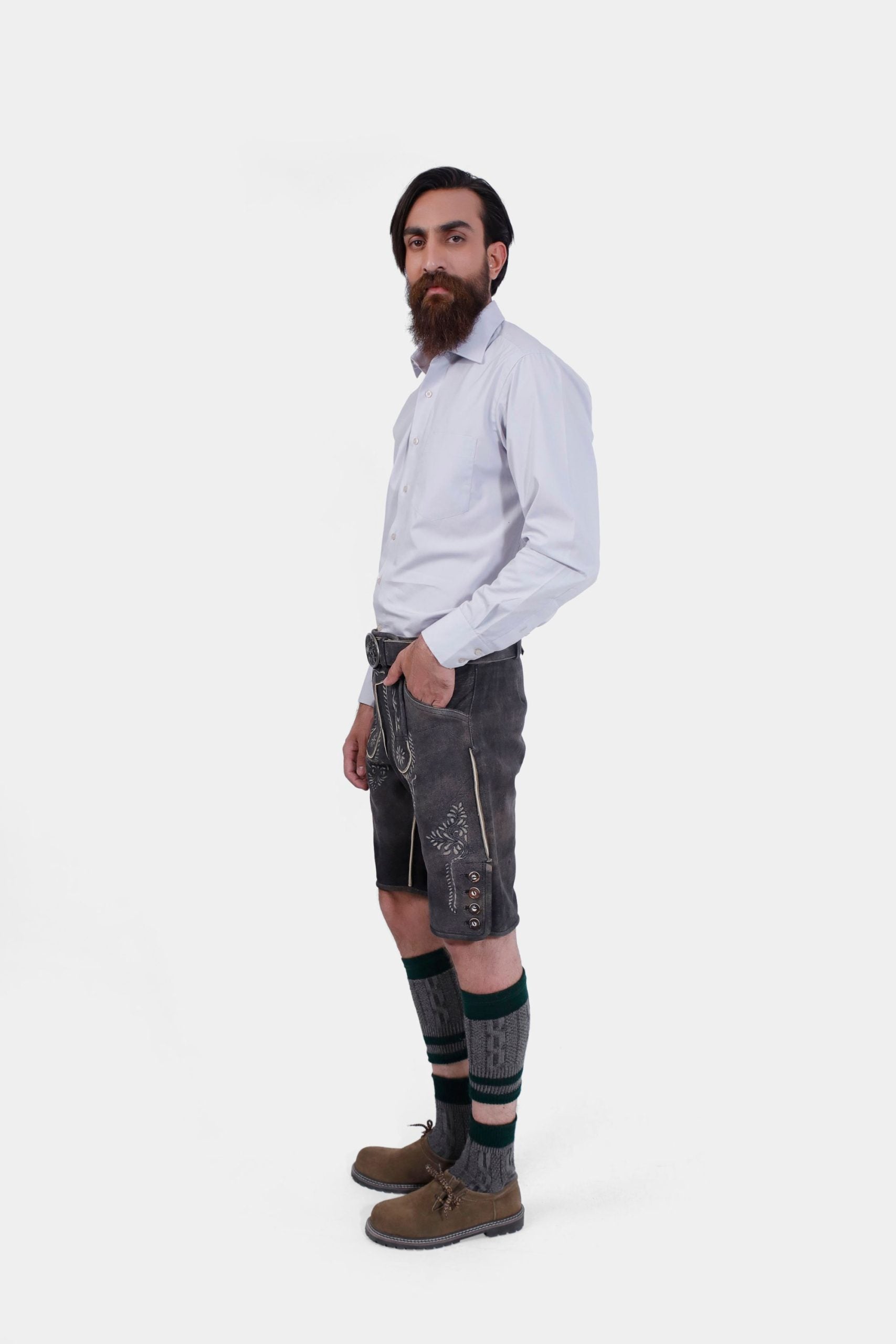 back view of a bearded man standing confidently in Black Forest Lederhosen, complete with knee-high socks and traditional shoes.