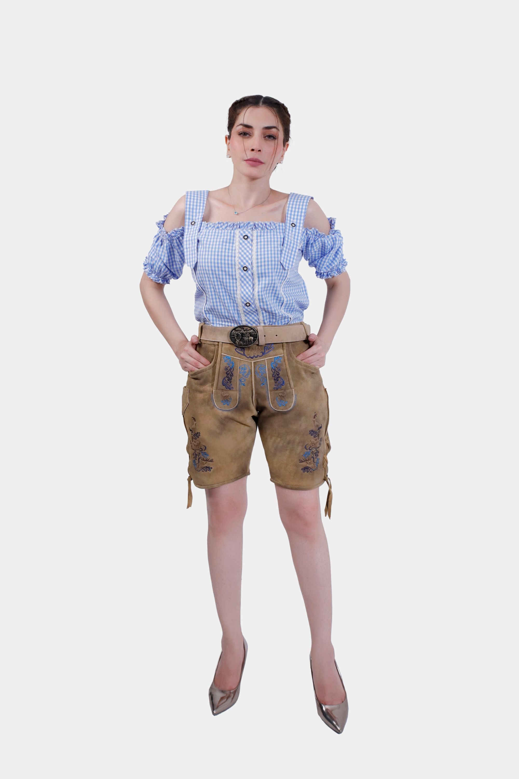 Full-body view of a woman wearing Clara Schumann Lederhosen and a blue and white checkered blouse. The Lederhosen feature blue embroidery and laces at the cuffs, styled with high heels.