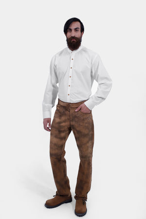 Complete front view of a man wearing traditional lederhosen long pants with intricate embroidery paired with a plain white shirt and brown shoes