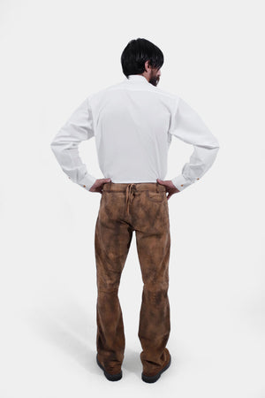 back view of a man wearing traditional lederhosen long pants paired with a plain white shirt