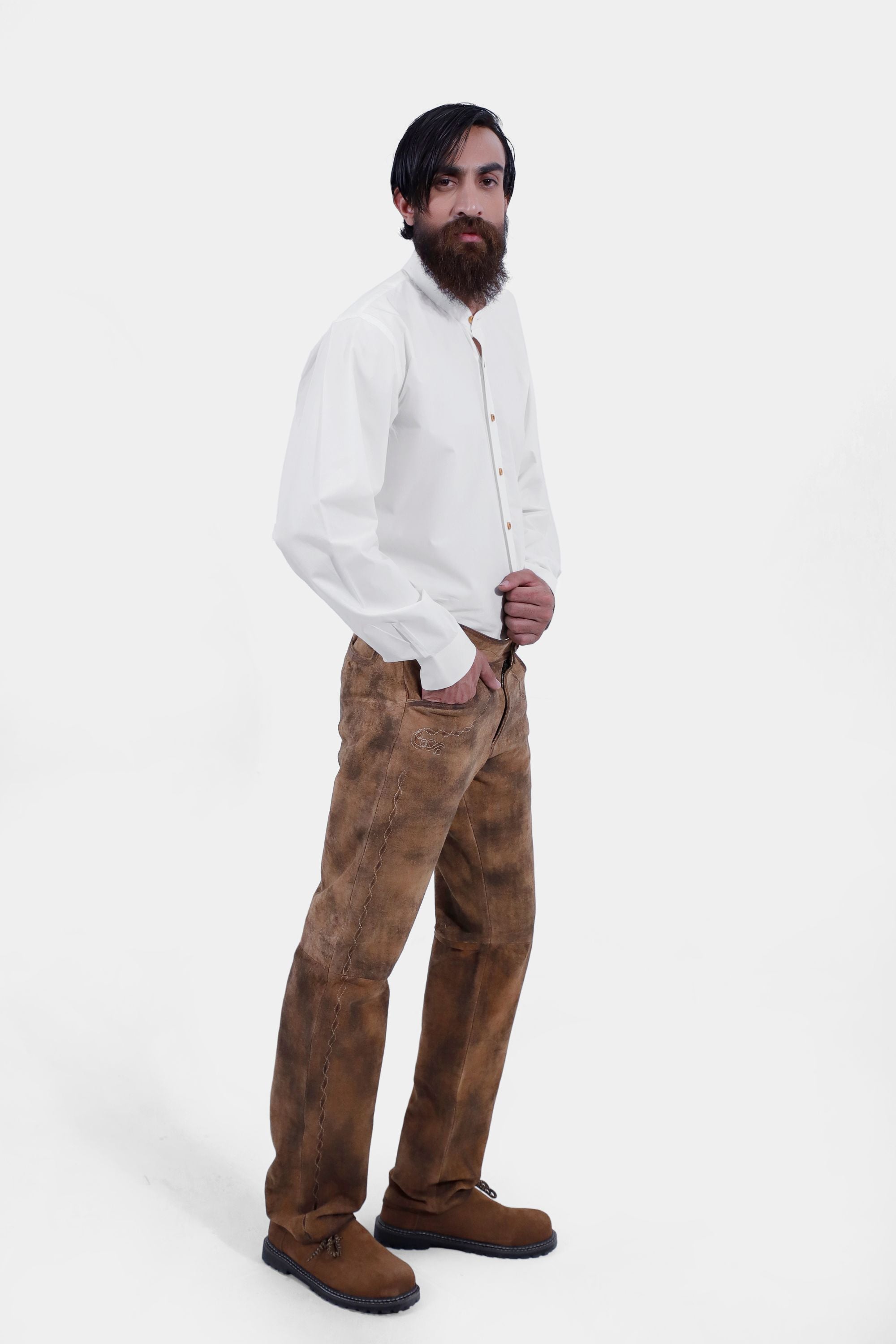 Side view of a man wearing traditional lederhosen long pants paired with a plain white shirt and brown shoes