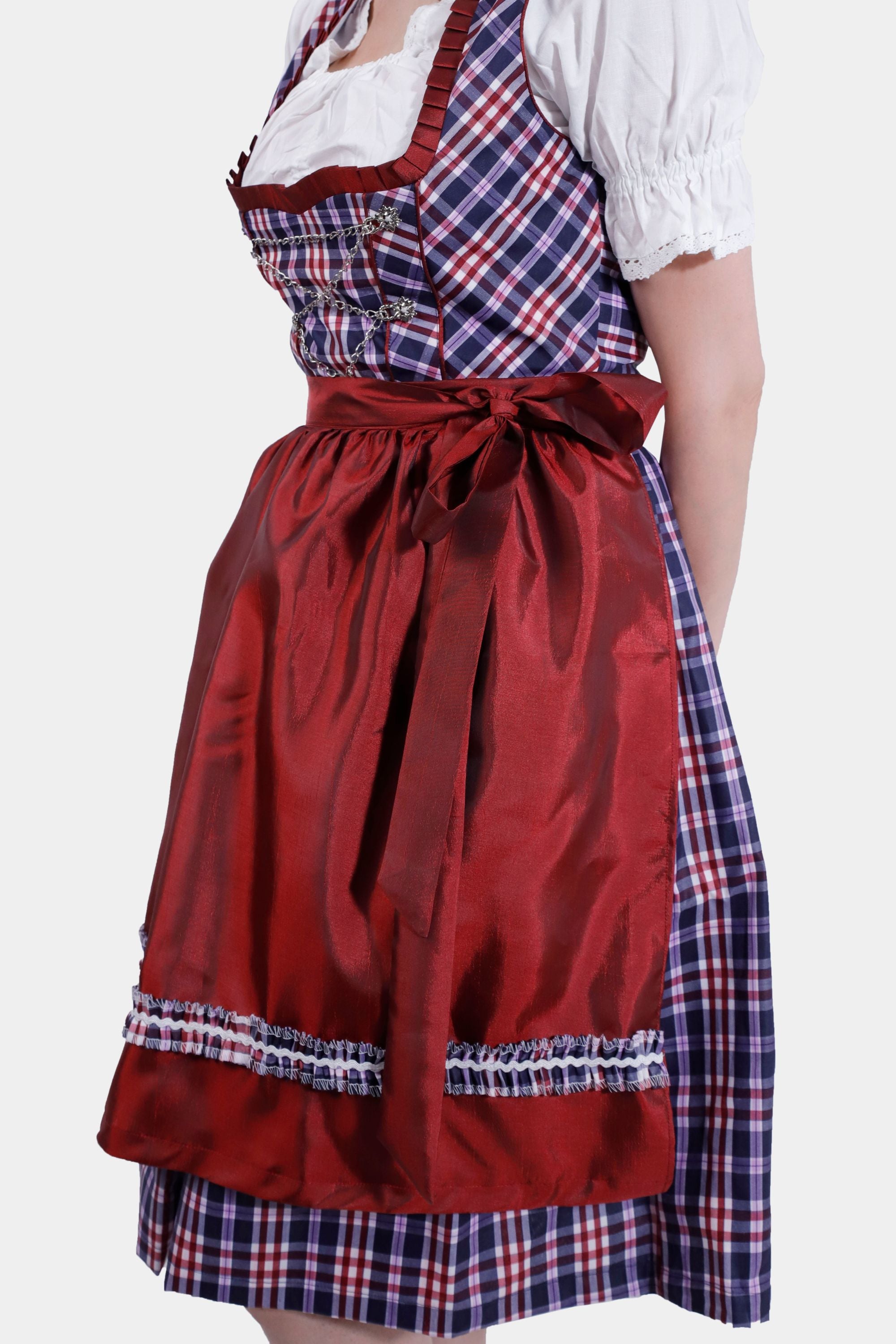 Side view of the dirndl dress highlighting the tied red apron and the pleated plaid skirt