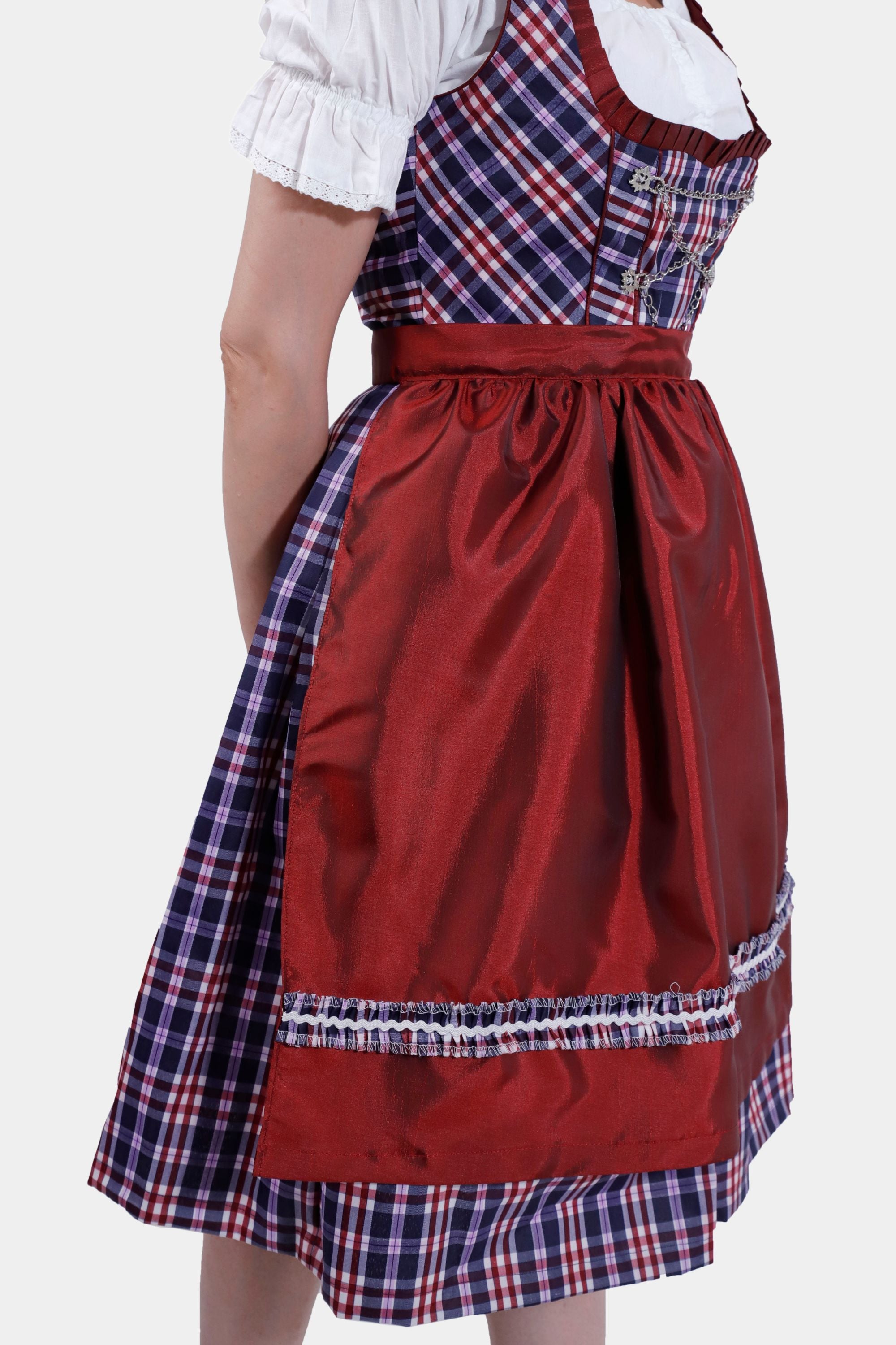 The other side view of the dirndl dress highlighting the tied red apron and the pleated plaid skirt