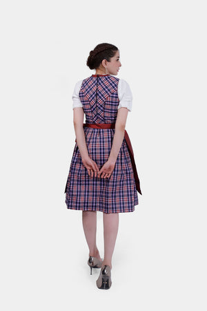 The dirndl dress is shown in full length from the back, with the red apron tied in a bow and paired with metallic high heels
