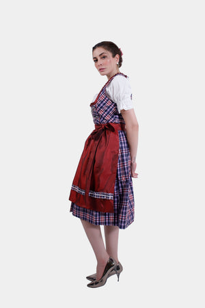 A side profile of the model wearing the dirndl dress, showcasing the white blouse with puffed sleeves and the flow of the plaid skirt.