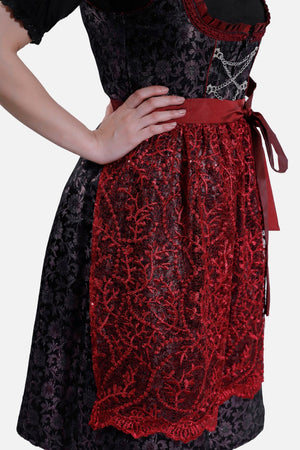 Detailed shot of the red lace apron tied in a bow at the side, showing off the delicate embroidery against the black skirt.
