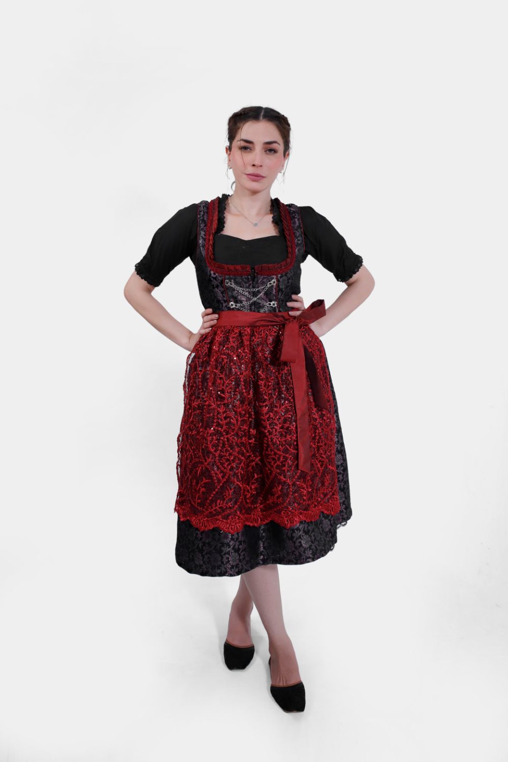 Full-length image of the woman in the dirndl, standing with her legs slightly crossed, wearing black flats and posing confidently.