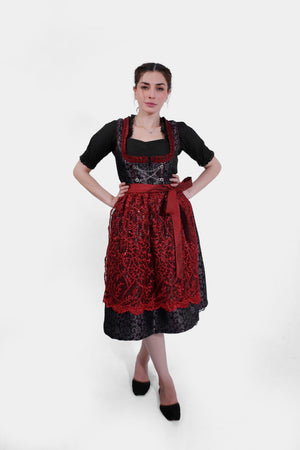 Full-length image of the woman in the dirndl, standing with her legs slightly crossed, wearing black flats and posing confidently.