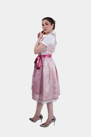 A side view of the pink dirndl dress, showcasing the layered lace apron and satin ribbon belt, paired with metallic heels.