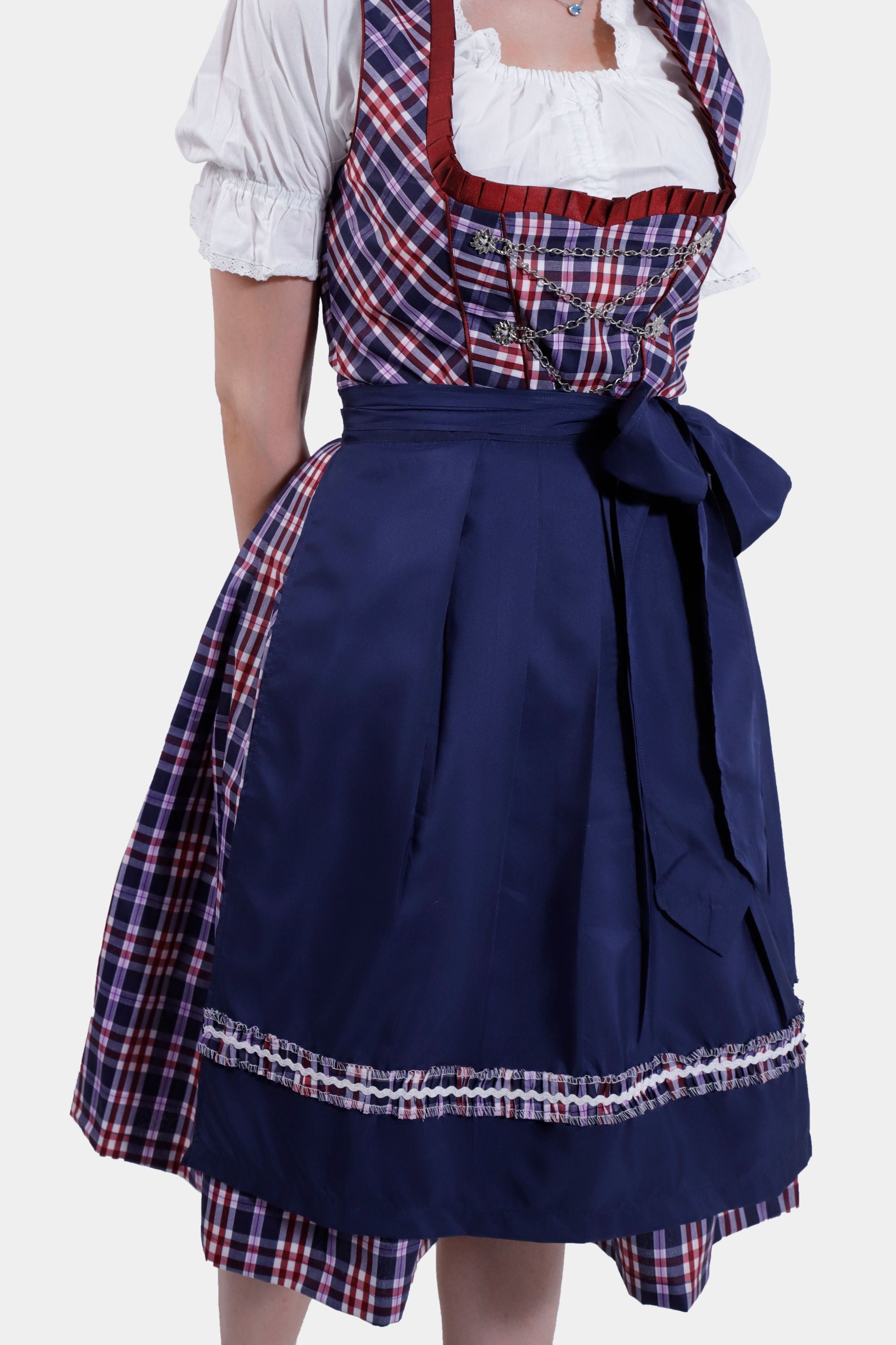 Close-up of the navy blue apron tied into a large bow, showing the plaid underlay and the intricate detailing of the Dirndl dress fabric.