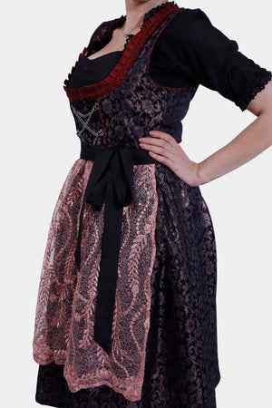 Side view of the dirndl dress, highlighting the black bodice with red trim, tied pink lace apron, and intricate floral patterns on the skirt.