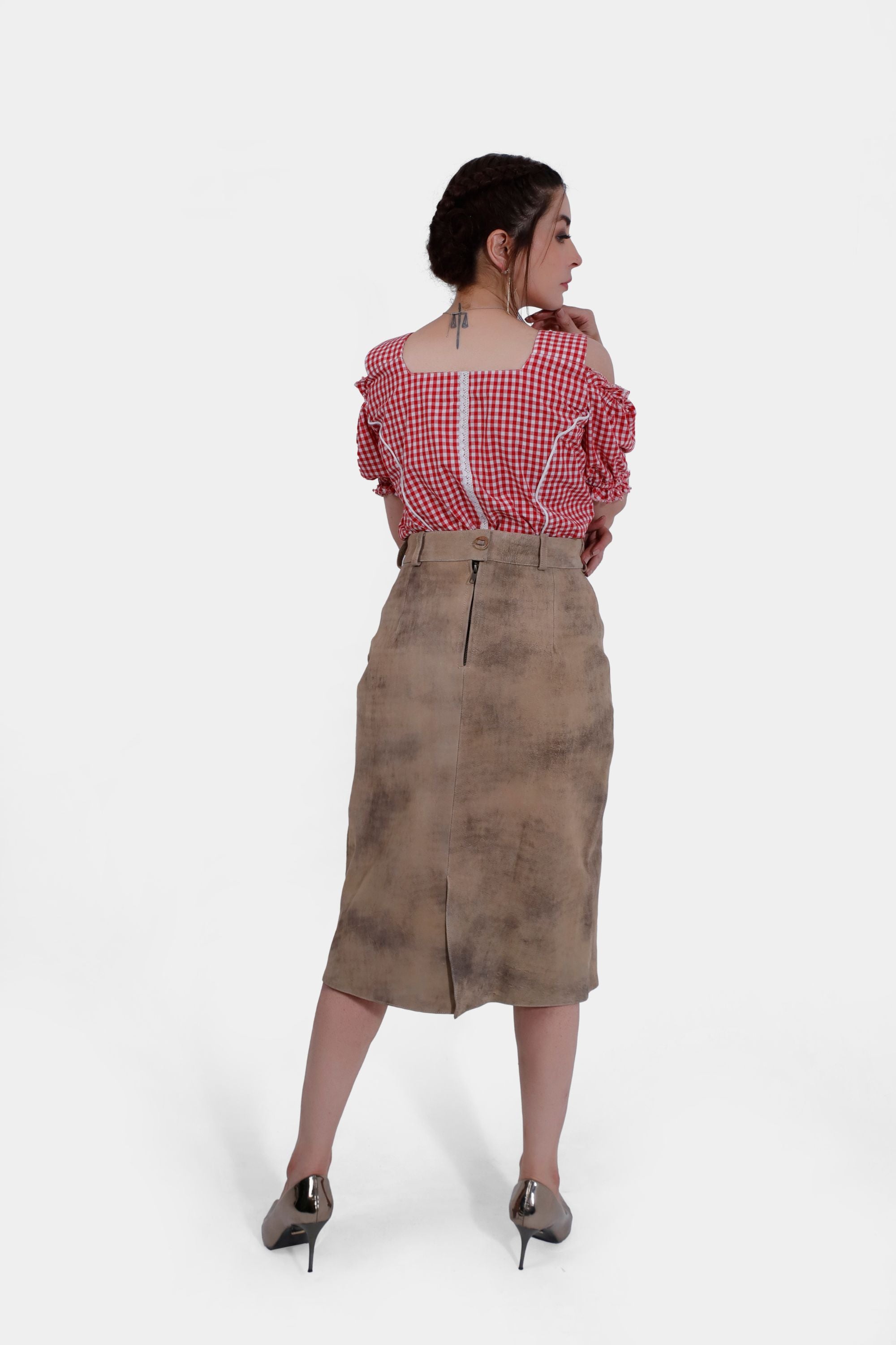 Back view of the woman wearing the red and white checkered blouse and beige leather skirt. The back of the blouse has a zipper, and the skirt features a slit at the back.