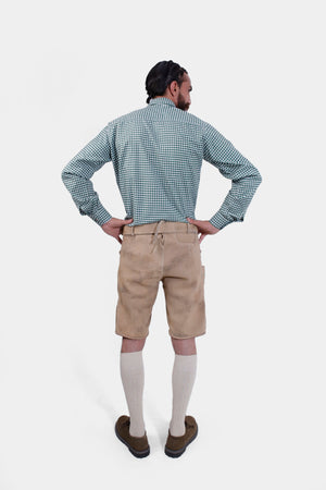 Rear view of a man wearing a green checkered shirt and beige lederhosen, hands on hips, highlighting the back design.