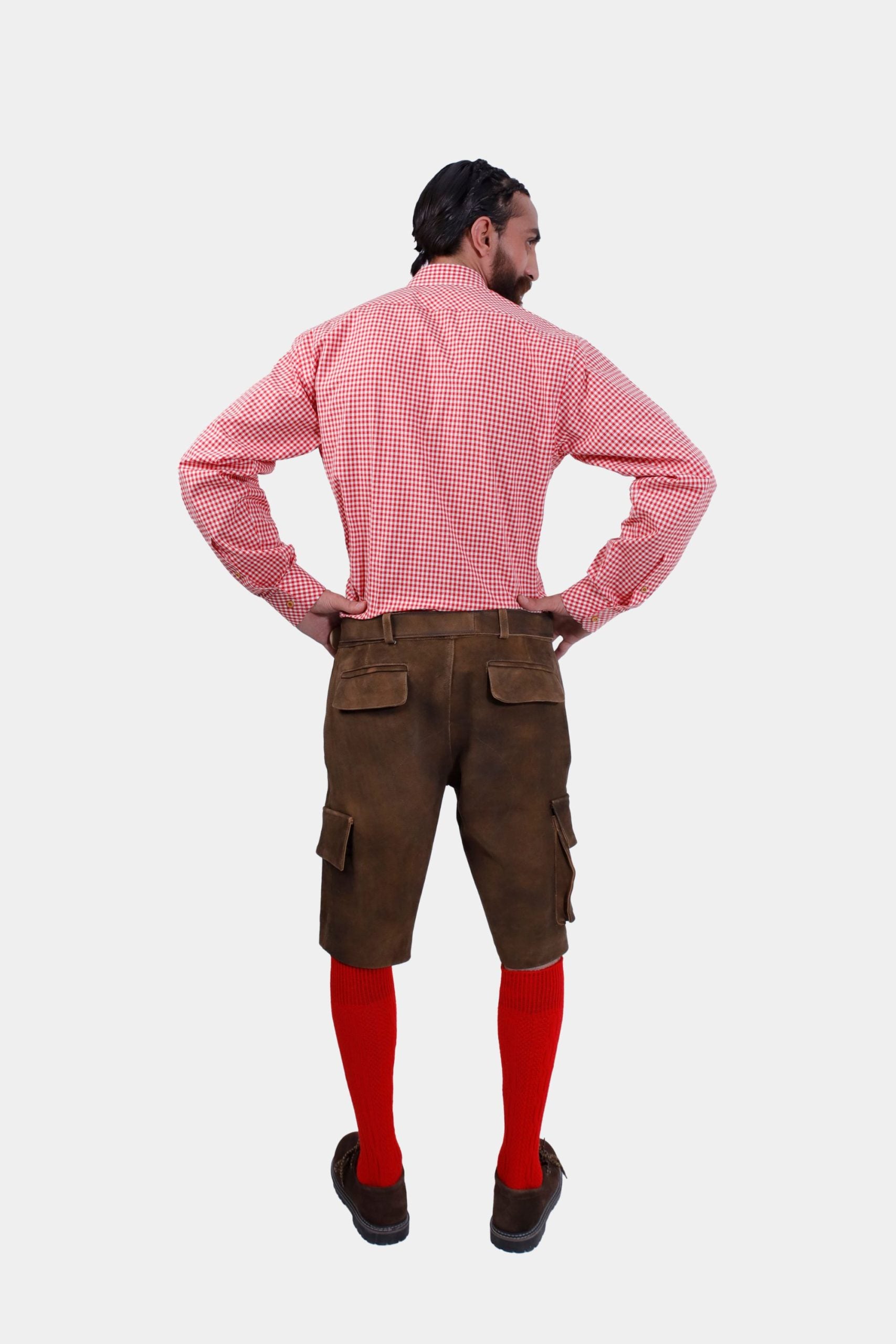 A full-length back view of the man in brown leather lederhosen and red checkered shirt, with red knee-high socks and brown shoes. ​