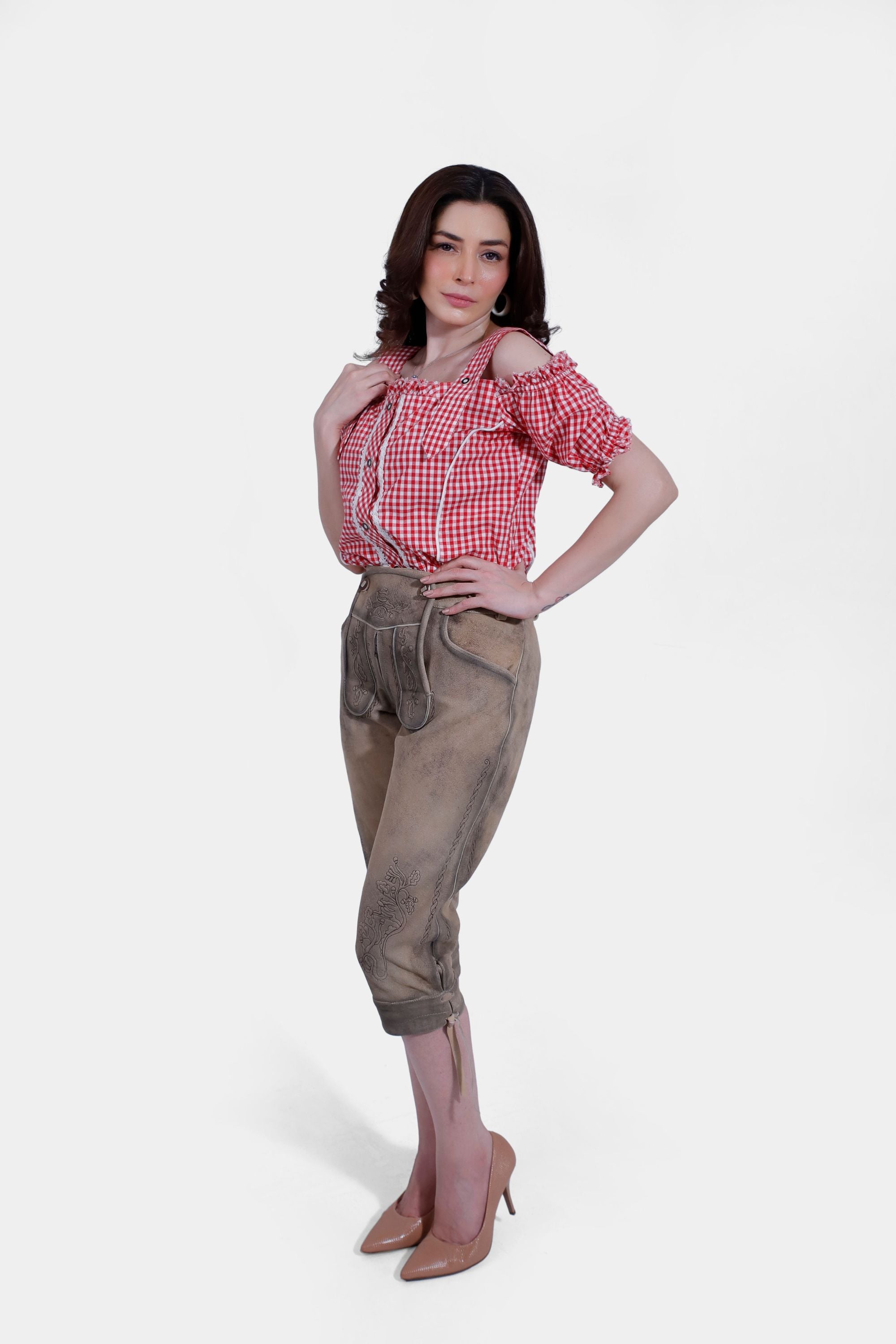 Back view of a woman in a red and white checkered blouse and beige lederhosen, showing the fit and details of the lederhosen from behind.