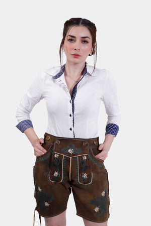 Image showing a woman wearing a traditional Bavarian outfit consisting of a white shirt with a polka dot collar and cuffs, paired with brown leather shorts (lederhosen) adorned with intricate embroidery.