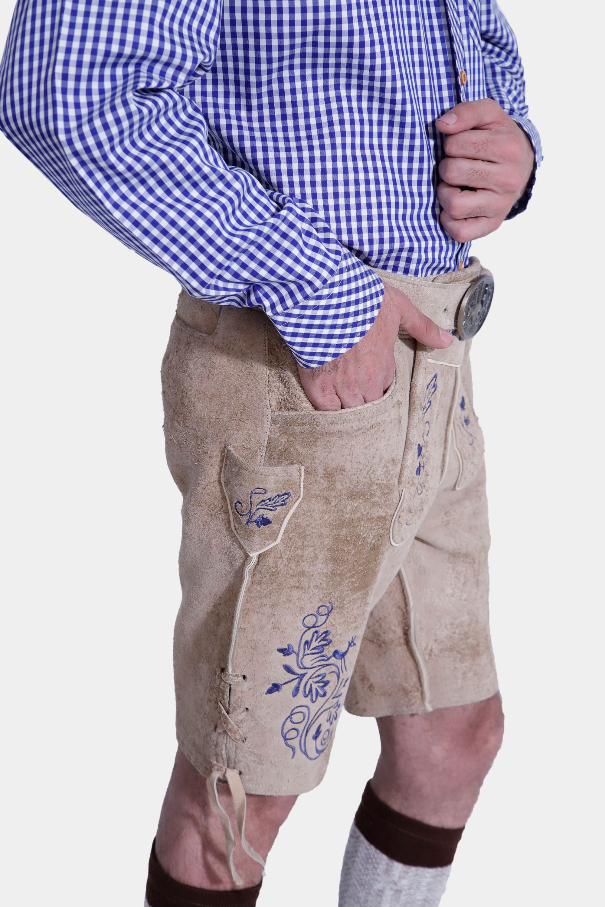 Closed side view of a man in light beige lederhosen with blue embroidery, front and back pockets, and a side knife pocket